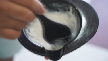 Kuaför saç boyası yapar, sarışını, saç kökünü boyar. Fırçayı kullanıyor. Yakın görüş. Kuaförlerin elleri beyaz eldivenli. Berber dükkanı, kuaför salonu.