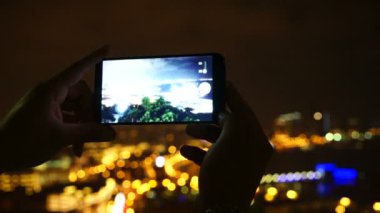 Akıllı Telefonlu Kadın Elleri Gece Şehri 'nin Fotoğrafı ya da Videosu.