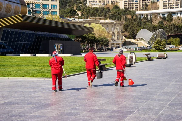 Street cleaners in red overalls in a city Park