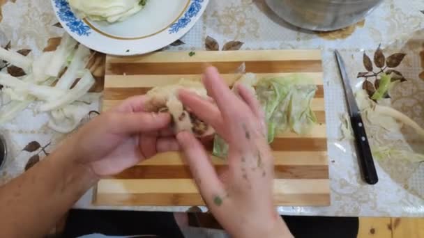 Μια γυναίκα μαγείρισσα ετοιμάζει λάχανο ρολά και κρέας στο τραπέζι στην κουζίνα. — Αρχείο Βίντεο