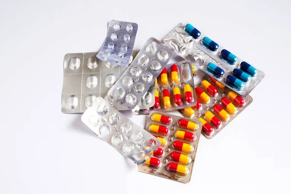 Beyaz arka planda bir sürü ilaç hapı var.