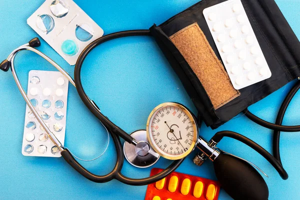 血圧計と赤い心臓と青い背景の丸薬 — ストック写真