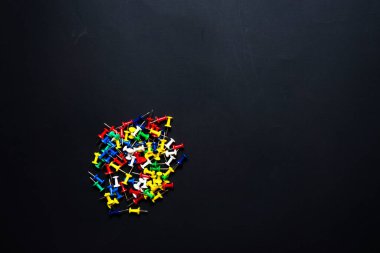 Siyah arka planda amcık renkli raptiyeler. iş kavramı