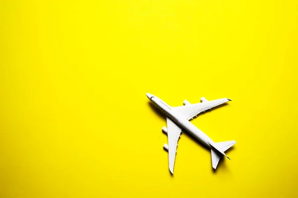 黄色の背景にミニチュアのおもちゃの飛行機 飛行機での旅 — ストック写真