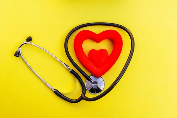 黄色の背景にトップビュー聴診器と赤いハート型 心臓や健康をチェックするためのコンセプトをチェック — ストック写真