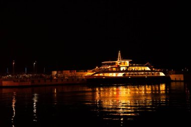 Gece liman şehrinde yürüyen yolcu gemisi