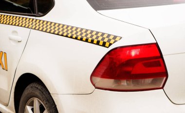 Beyaz taksi caddede dikiz aynasından duruyor.