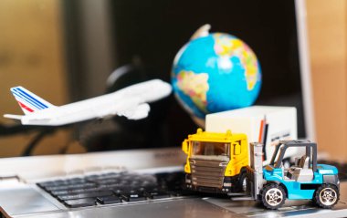 Çevrimiçi alışveriş kavramı için lojistik ve tedarik zinciri yönetimi: dünya, beyaz sarı kamyon, uçak, dizüstü bilgisayardaki forklift, mal veya ürünlerin teslimini resmediyor.