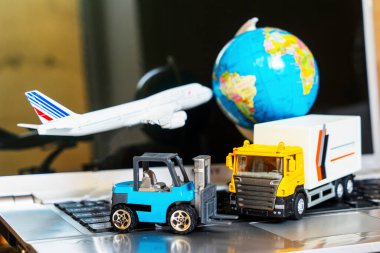 Çevrimiçi alışveriş kavramı için lojistik ve tedarik zinciri yönetimi: dünya, beyaz sarı kamyon, uçak, dizüstü bilgisayardaki forklift, mal veya ürünlerin teslimini resmediyor.