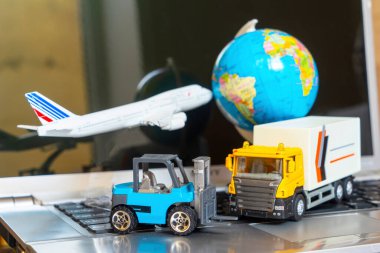 Çevrimiçi alışveriş kavramı için lojistik ve tedarik zinciri yönetimi: dünya, beyaz sarı kamyon, uçak, dizüstü bilgisayardaki forklift, mal veya ürünlerin teslimini resmediyor.