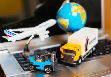 Çevrimiçi alışveriş kavramı için lojistik ve tedarik zinciri yönetimi: dünya, beyaz sarı kamyon, uçak, dizüstü bilgisayardaki forklift, mal veya ürünlerin teslimini resmediyor.