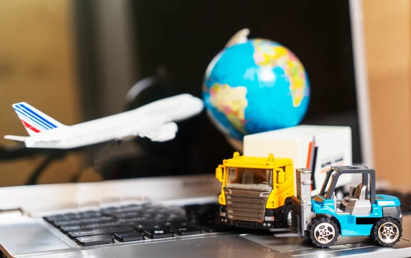 Logistics and supply chain management for online shopping concept: globe, white yellow truck, airplane, forklift on a laptop computer, depicts the delivery of goods or products.