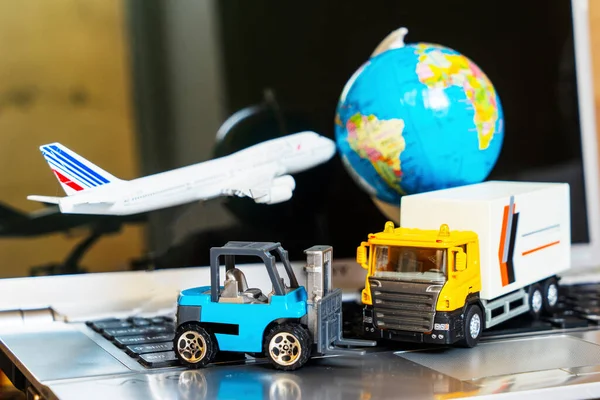 Çevrimiçi alışveriş kavramı için lojistik ve tedarik zinciri yönetimi: dünya, beyaz sarı kamyon, uçak, dizüstü bilgisayardaki forklift, mal veya ürünlerin teslimini resmediyor.