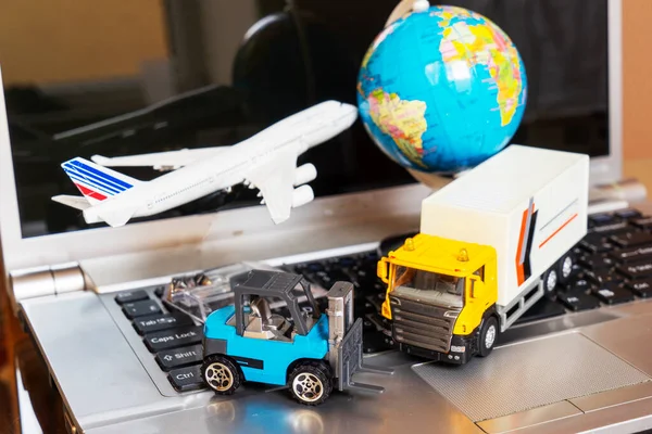 Çevrimiçi alışveriş kavramı için lojistik ve tedarik zinciri yönetimi: dünya, beyaz sarı kamyon, uçak, dizüstü bilgisayardaki forklift, mal veya ürünlerin teslimini resmediyor.