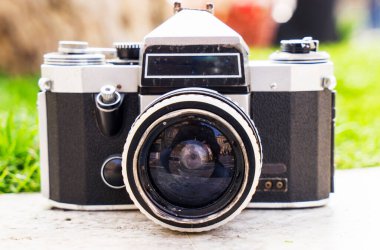 Doğanın bulanık arka planında, bir kaya üzerinde eski bir Sovyet film kamerası. Kameraya odaklanmış sığ alan derinliği. Açık havada. Retro resim biçimi.