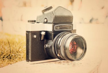 Doğanın bulanık arka planında, bir kaya üzerinde eski bir Sovyet film kamerası. Kameraya odaklanmış sığ alan derinliği. Açık havada. Retro resim biçimi.