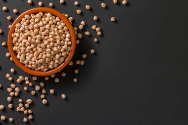 Siyah arka planda civciv bezelyesi olan bir kasenin en üst görüntüsü.