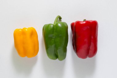 Beyaz arka planda üç kırmızı, yeşil ve sarı biber.