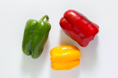 Beyaz arka planda üç kırmızı, yeşil ve sarı biber.