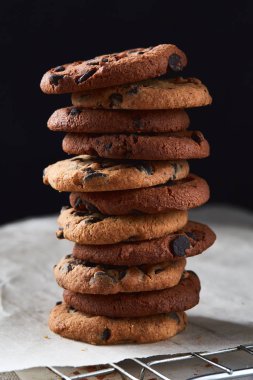 El yapımı çikolata kurabiye pişirme kağıdı üzerinde çikolata parçaları ile yığını. Sağlıklı kahvaltı için doğal el yapımı organik yılan