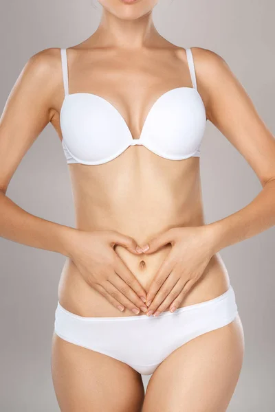 stock image Woman health problem. Closeup of female with fit slim body in panties and bra suffering from pain and holding her hands on the stomach. Digestive disorders, period pain, health issues concept