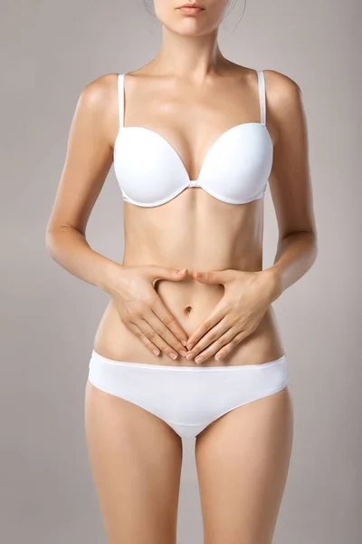 Woman health problem. Closeup of female with fit slim body in panties and bra suffering from pain and holding her hands on the stomach. Digestive disorders, period pain, health issues concept — Stock Image Woman Health Problem Closeup Female Fit Slim Body Panties Bra Stock Photo