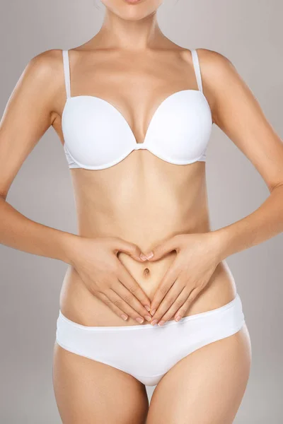 Woman health problem. Closeup of female with fit slim body in panties and bra suffering from pain and holding her hands on the stomach. Digestive disorders, period pain, health issues concept — Stock Image Woman Health Problem Closeup Female Fit Slim Body Panties Bra Stock Picture
