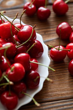 Bir sürü tatlı kiraz beyaz vintage plaka çul ve ahşap masa. Vegan rasyon, sağlıklı doğal beslenme, çiğ gıda katkı maddeleri ve pişirme
