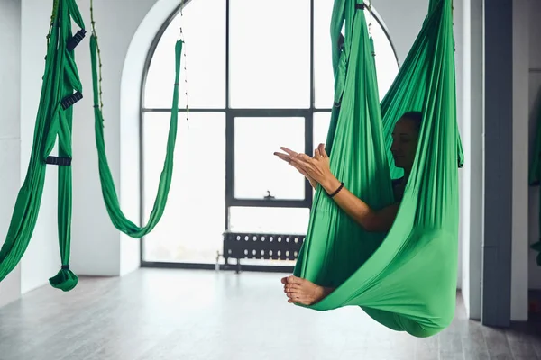 The interior shooting of an adult woman practices different inversion antigravity yoga with a hammock in yoga studio. The balance between mental and physical, one person effort and achievement concept