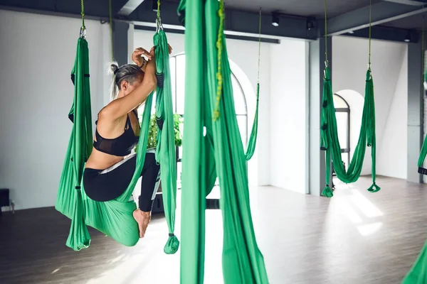 The interior shooting of an adult woman practices different inversion antigravity yoga with a hammock in yoga studio. The balance between mental and physical, one person effort and achievement concept