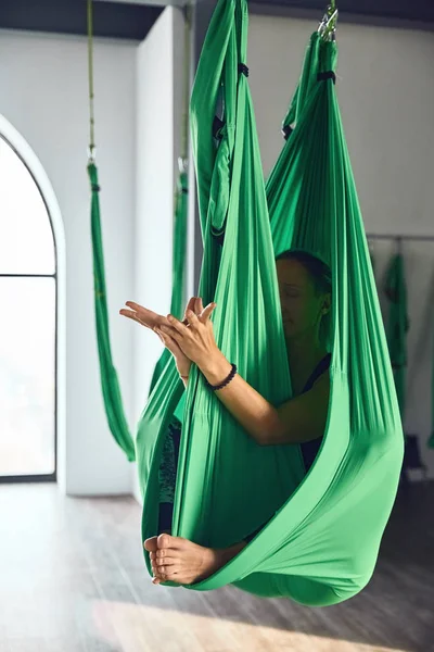 一个成年妇女的内部拍摄练习不同的倒置反重力瑜伽与吊床在瑜伽工作室 精神和身体 一个人的努力和成就概念之间的平衡 — 图库照片