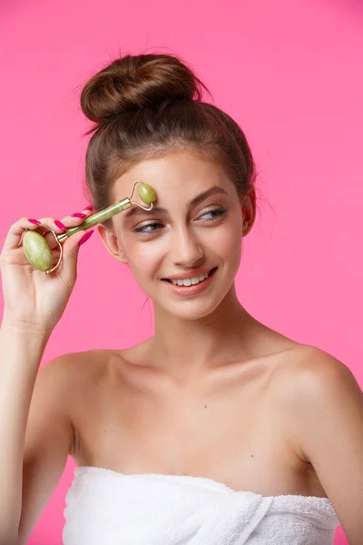 Mulher aplicando rolo de jade para massagem facial — Fotografia de Stock