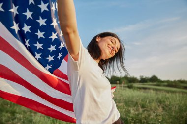 4 Temmuz. 4 Temmuz 'da. Amerikan bayrağıyla güzel bir simgeye karşı Amerikan bayrağı taşıyan bir kadın. Bağımsızlık Günü. Güzel gün batımı ışığı. Vatansever bayram, demokrasi saygı ve gazi saygı kavramı