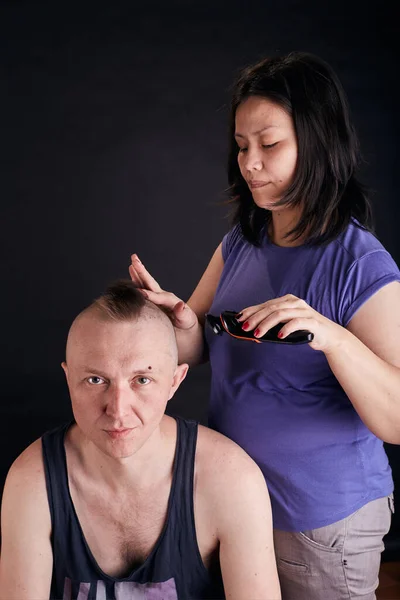 Wife doing haircut for husband at home while Covid-19 quarantine. Self isolation family lifestyle.