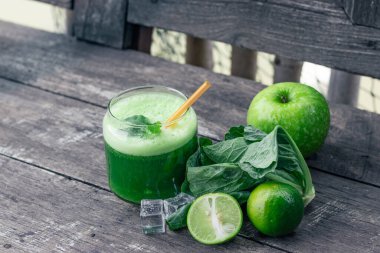 Kırsal ahşap masada cam ve lahana yapraklı yeşil elma püresi. Yaz Detox sallama arkaplanı