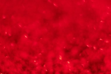 Kırmızı ışıltılı arka planda Bokeh ışıkları var. Yeni yıl, Noel tatilleri ve yıldönümleri için kutlama konsepti.