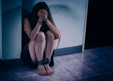 Genç bir kadın şiddete maruz kalıyor, yere oturuyor, ellerini kelepçeleyerek yüzünü kapatıyor. Elleri damarlar ve yaralar, bacakları bir iple bağlanmış. Travma sonrası stres bozukluğu.