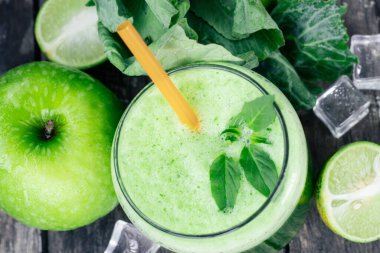 Kırsal ahşap masada cam ve lahana yapraklı yeşil elma püresi. Yaz Detox sallama arkaplanı