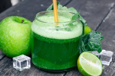 Kırsal ahşap masada cam ve lahana yapraklı yeşil elma püresi. Yaz Detox sallama arkaplanı