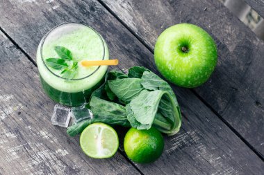 Kırsal ahşap masada cam ve lahana yapraklı yeşil elma püresi. Yaz Detox sallama arkaplanı