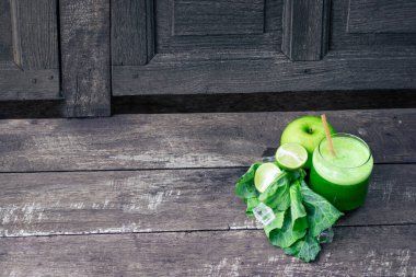 Kırsal ahşap masada cam ve lahana yapraklı yeşil elma püresi. Yaz Detox sallama arkaplanı