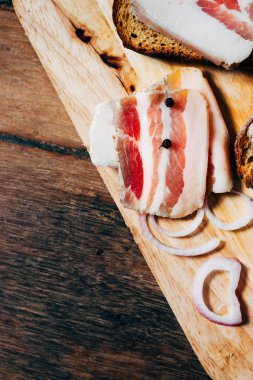 Ahşap masadaki masa örtüsünün üzerinde domuz yağlı ve siyah ekmekli sandviç.