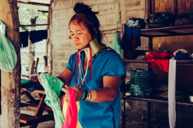 Uzun Boylu Kadın Tayland 'ın kuzeyindeki kabile köyünde evinin önünde kumaş dokuyordu..