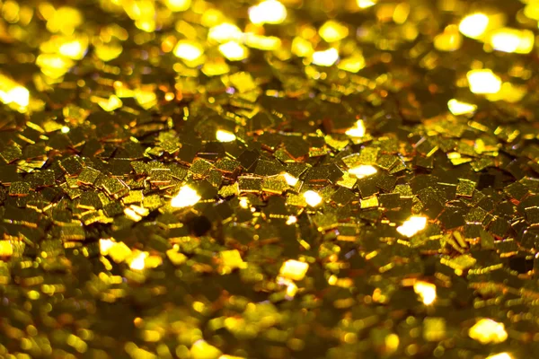 Gold glitter texture. Festive sparkling sequins background closeup. Brilliant shiny walpaper for the day of St. Valentine, New Year and Christmas Holidays.