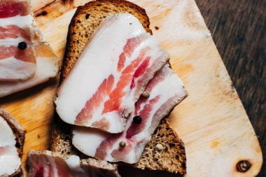 Ahşap masadaki masa örtüsünün üzerinde domuz yağlı ve siyah ekmekli sandviç.