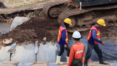 Chiang Rai / Tayland - 20 Ağustos 2018, sel sonrası yollar rehabilitasyonu. İşçiler ve beton borular. Bir kişi beton bir boru boyunca yürür ve jüt torbalarını çıkarır..