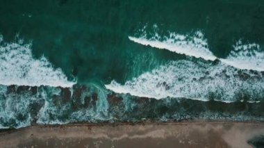 Yukarıda, mercan resifinin kıyısındaki dalgaların üzerindeki köpük dokusuna sahip turkuaz okyanus. 4k 'lık havadan uçuş videosu.
