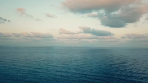 Modré uklidňující vlny oceánu při západu slunce s zataženou oblohou. Video 4k.