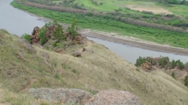 Yaz, gün, tepenin üzerinden ön planda bir kayayla birlikte nehir manzarası. Buryatia, Selenga nehri..