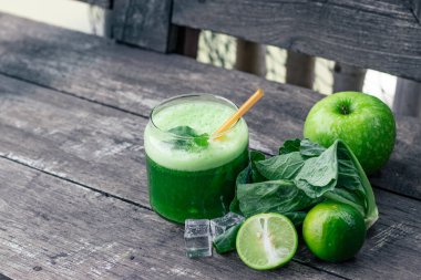 Kırsal ahşap masada cam ve lahana yapraklı yeşil elma püresi. Yaz Detox sallama arkaplanı